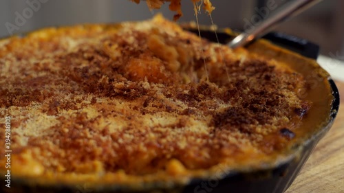 Fork dig in a cast iron skillet filled with mac and cheese, a classic American dish, baked in the oven with crispy breadcrumbs on top photo
