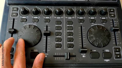 A DJ interface for dj'ing from computer is seen. A fader is raised and de deck is turned forward to speed up the song. photo