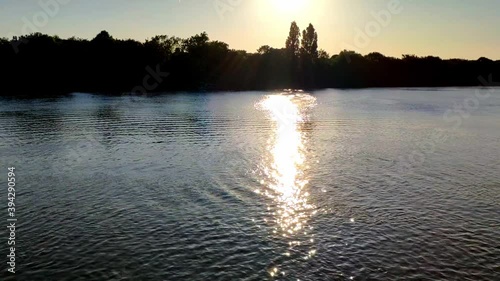 River Thames around Kew area on a Summer sunny sunset. The sun is reflecting beautifully on the water creating a lot of contrast on the horizon. photo