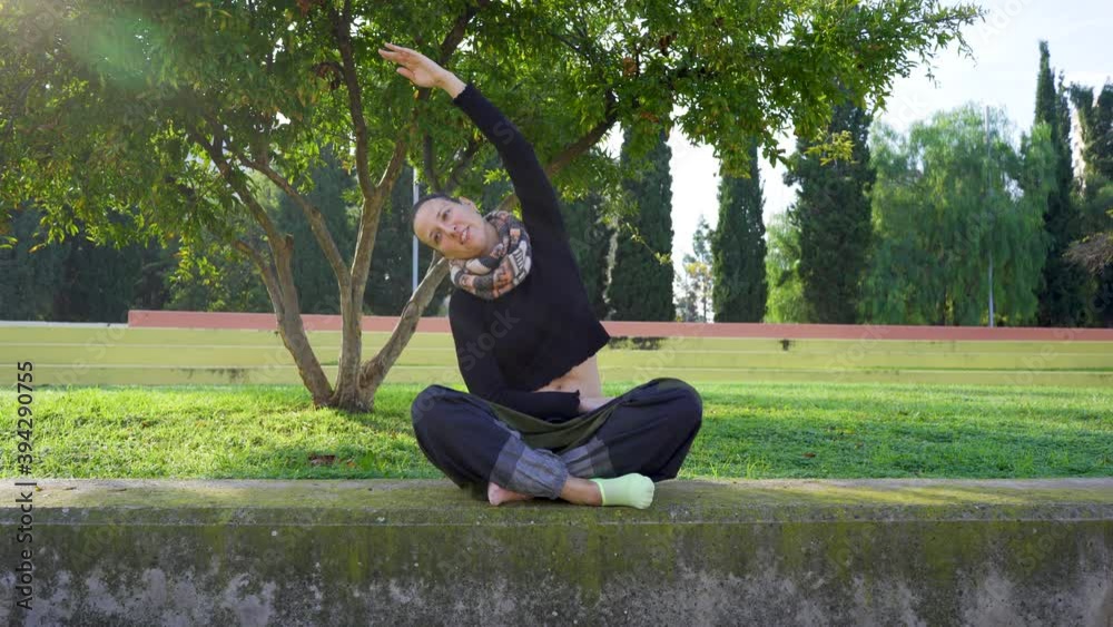 Yoga teacher stretching with her arm and sitting in the lotus position Yoga teacher stretching with her arm and sitting in the lotus position