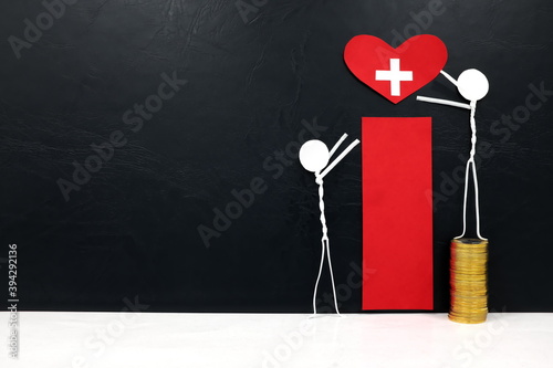 Stick man figure reaching for a red heart shape with cross cutout while stepping on stack of coins. Health, healthcare, medical care and hospital access inequality concept