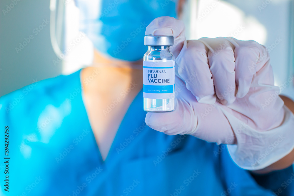 A health worker holding a bottle of Covid-19, Coronavirus or SARS-CoV-2 vaccine on a Sterile Transparent Vial with a white and blue label a white globes A health worker holding a bottle of Covid-19, Coronavirus or SARS-CoV-2 vaccine on a Sterile Transparent Vial with a white and blue label a white globes