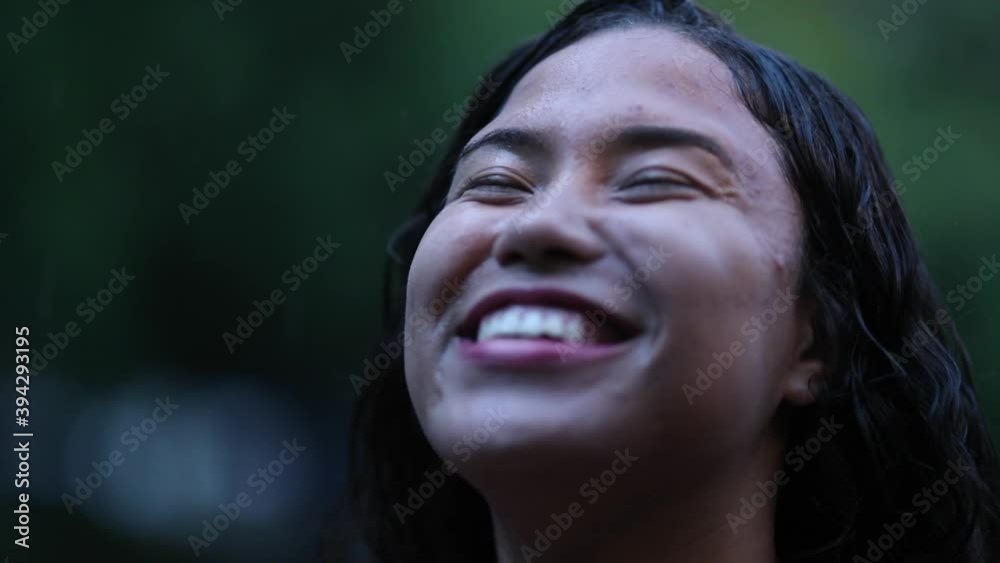 Woman standing outside in rain shower, close-up smiling face feeling happiness and freedom Woman standing outside in rain shower, close-up smiling face feeling happiness and freedom