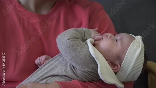 A young father holds a baby in his arms. The person in pink sweater cradles a child close-up photo