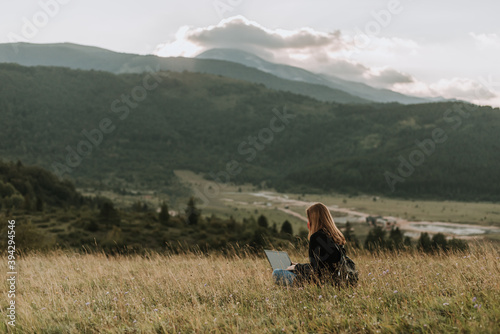 Woman with mask working on laptop, remote location in nature