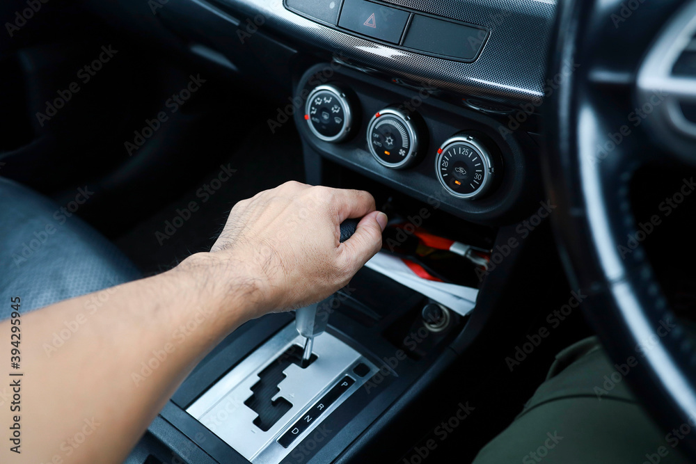 A hand of a person holding the gear level inside the car 