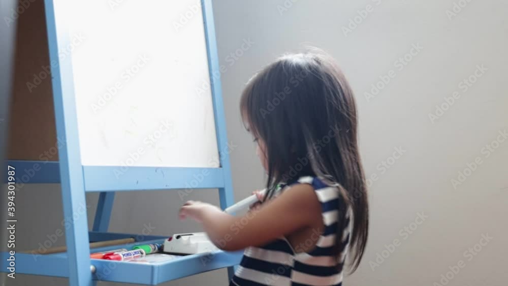 little asian girl painting with marker pen on whiteboard.asian child student back to school or kid girl draw or write. little asian girl painting with marker pen on whiteboard.asian child student back to school or kid girl draw or write.