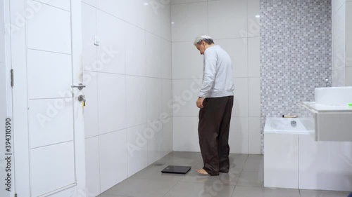 Wallpaper Mural Old man measuring his weight with a scale on the morning in the bathroom at home. Shot in 4k resolution Torontodigital.ca