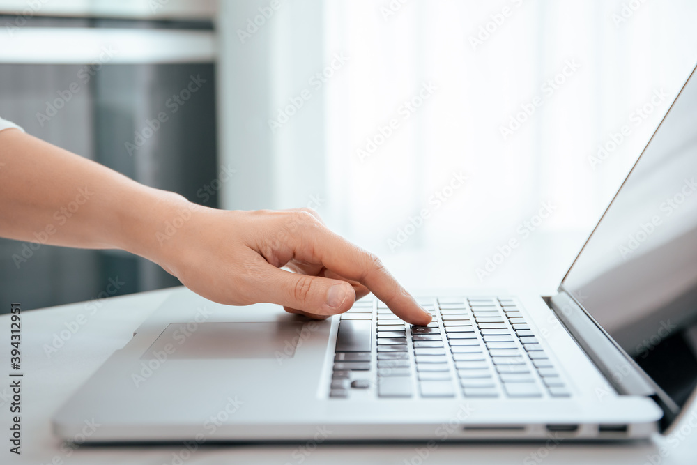 Unrecognizable woman pressing on the laptop computer keyboard by using her forefinger. Unrecognizable woman pressing on the laptop computer keyboard by using her forefinger.