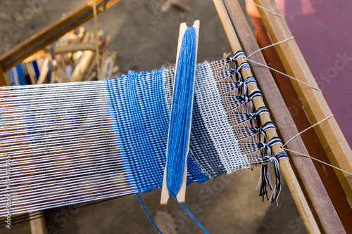 Blue wool being woven into a piece of fabric on a manual loom