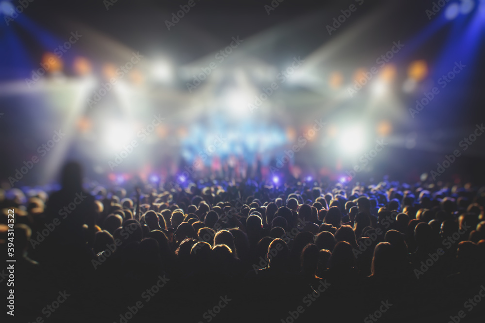 A crowded concert hall with scene stage lights, rock show performance, with people silhouette, colourful confetti explosion fired on dance floor air during a concert festival