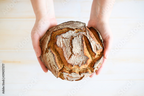Rustic wholegrain sourdough bread, hands holding fresh loaf.
