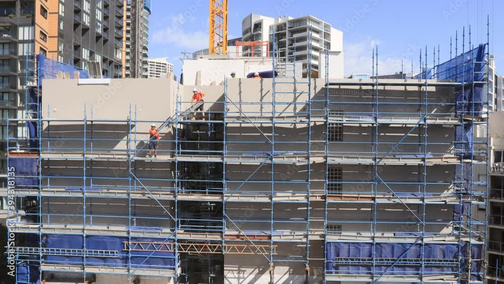 Construction workers on scaffolds building high-rise house as timelapse in 4k.
