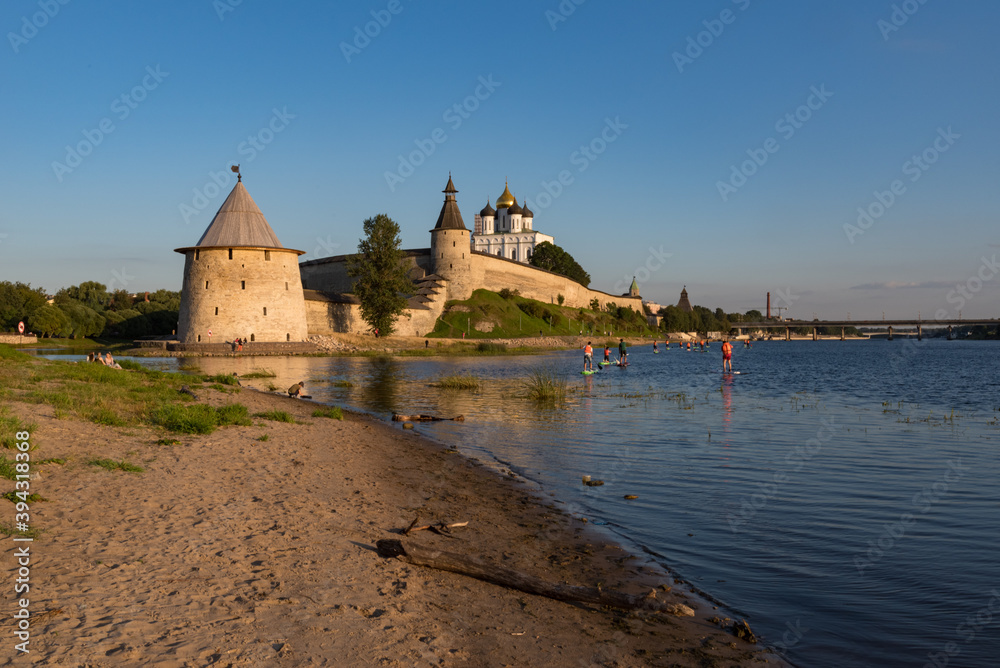 SUP surfers on Velikaya river. Towers and wall of Pskov Kremlin at background. Pskov, Russia.