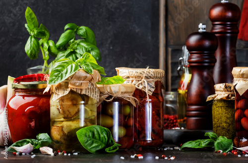 Fermented, pickled, marinated preserved vegetarian italian snacks and sauces. Organic sun-dried tomatoes, artichokes, capers, olives, marinara sauces, pesto in jars with spice and herbs photo