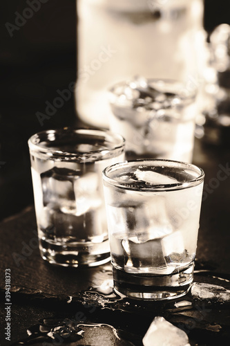 Frozen Vodka in shot glasses on black background, iced strong drink