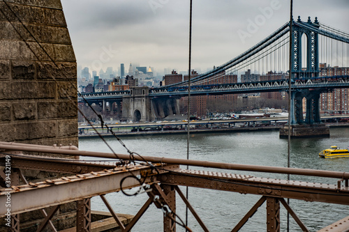 View of Manhattan bridge from Brooklyn bridge. Buildings from Brooklyn in the background.