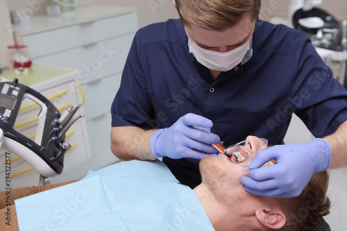 Wallpaper Mural Doctor orthodontist applies gel to teeth. Dilator for the oral cavity. Preparation of the oral cavity before placing braces or braces. Care and health care concept. Photo in the dental office. Torontodigital.ca