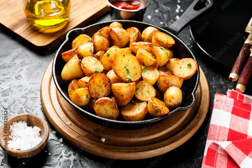 Roasted baby potatoes in iron skillet on black background. 