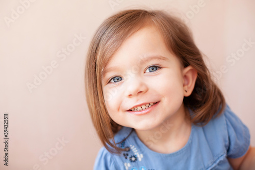 portrait of a european girl with blond hair and blue eyes in neutral colors looks into the frame with a smile