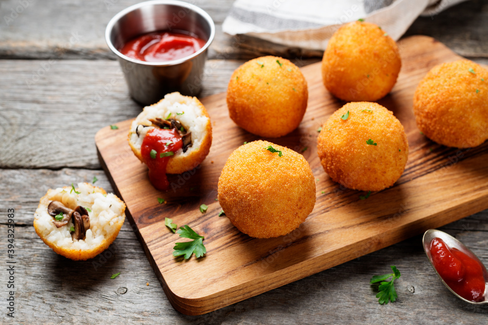 Homemade Fried Risotto Arancini stuffed with mushroom and parmesan cheese, served with tomato sauce.