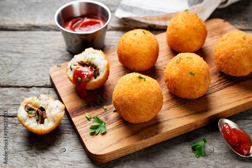 Homemade Fried Risotto Arancini stuffed with mushroom and parmesan cheese  served with tomato sauce.