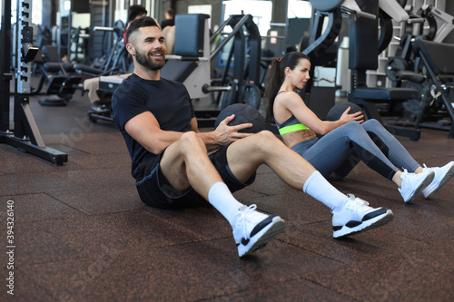 Sport young people sitting on a gym floor working out together with a medicine ball during an abdominal exercise session.