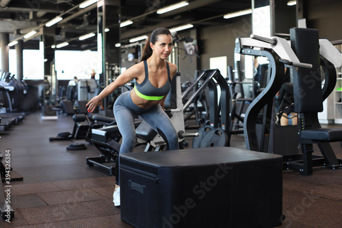 Cute athletic brunette doing jumping exercises in a cross-training gym.