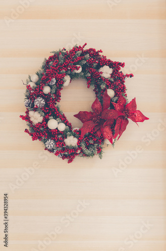 Christmas wreath hanging on a wooden door. Toned image.