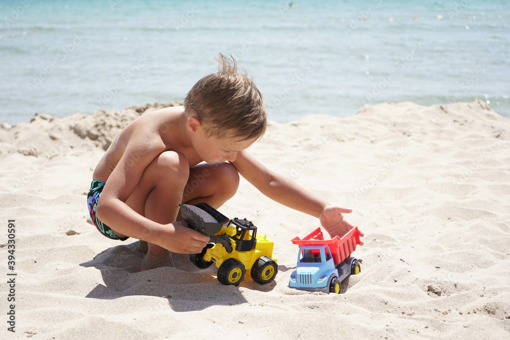 cute boy on the beach playing with toys. A child plays against the background of the azure sea on a Sunny summer day. cute boy on the beach playing with toys. A child plays against the background of the azure sea on a Sunny summer day.