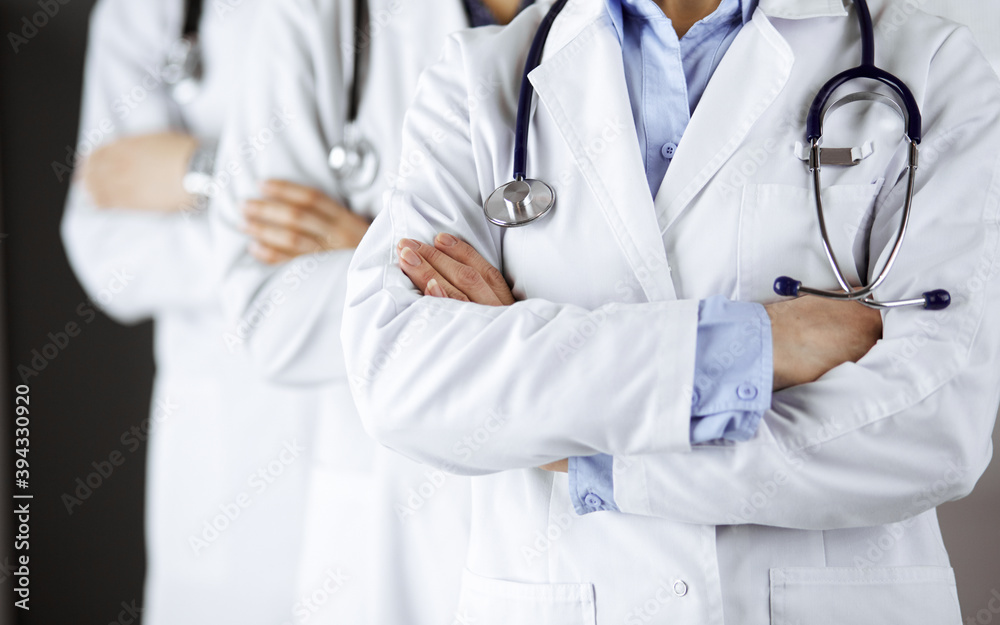 Group of modern doctors standing as a team with arms crossed in hospital office and ready to help patients. Medical help, insurance in health care, best disease treatment and medicine concept Group of modern doctors standing as a team with arms crossed in hospital office and ready to help patients. Medical help, insurance in health care, best disease treatment and medicine concept
