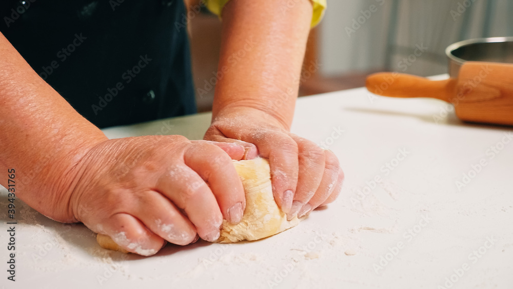 Close up of grandmother hands kneading on table in home kitchen. Retired elderly baker with bonete mixing ingredients with sifted wheat flour kneading for baking traditional cake and bread. Close up of grandmother hands kneading on table in home kitchen. Retired elderly baker with bonete mixing ingredients with sifted wheat flour kneading for baking traditional cake and bread.