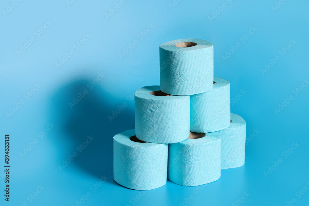 A stack of rolls of toilet paper on a blue background with copy space. A stack of rolls of toilet paper on a blue background with copy space.