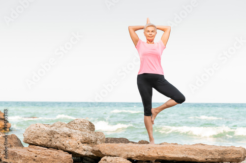 A woman standing on a rocky beach in yoga position