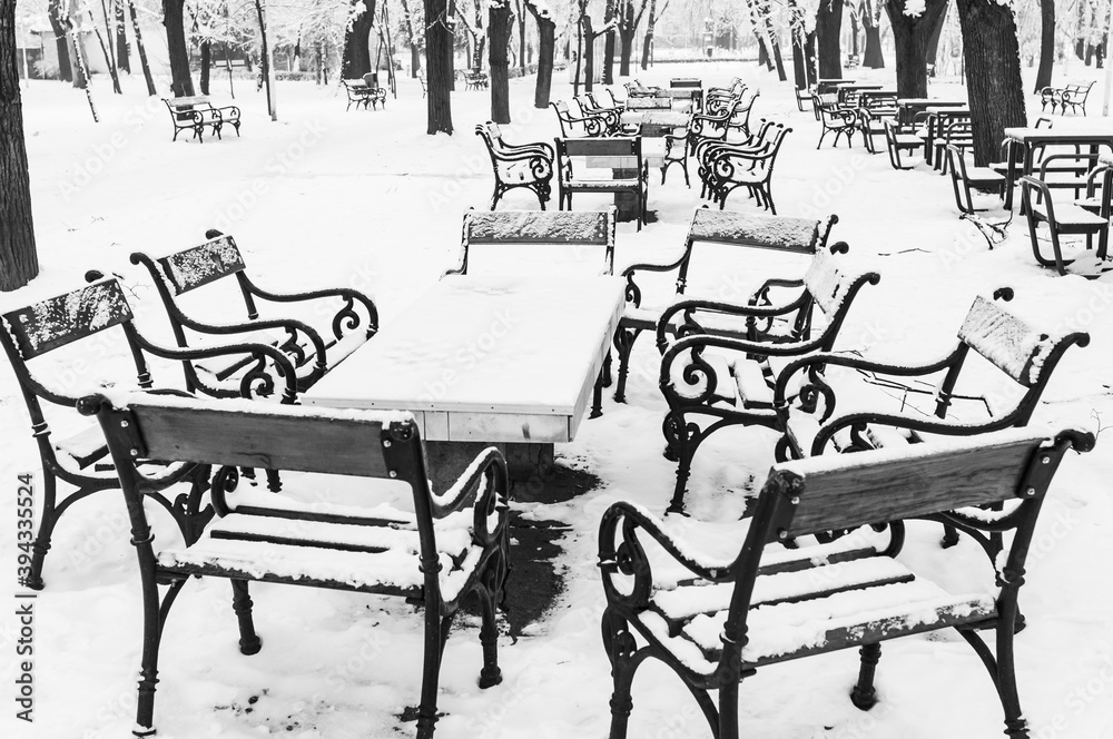 park in the middle of the winter with snow on benches in black and white