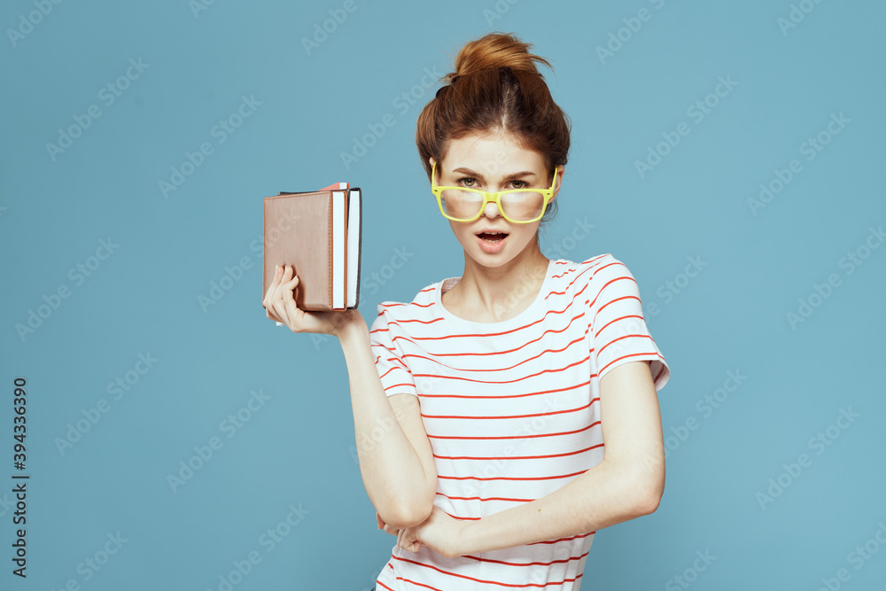 Female student with books in hands on a blue background and yellow glasses model hairstyle cropped view
