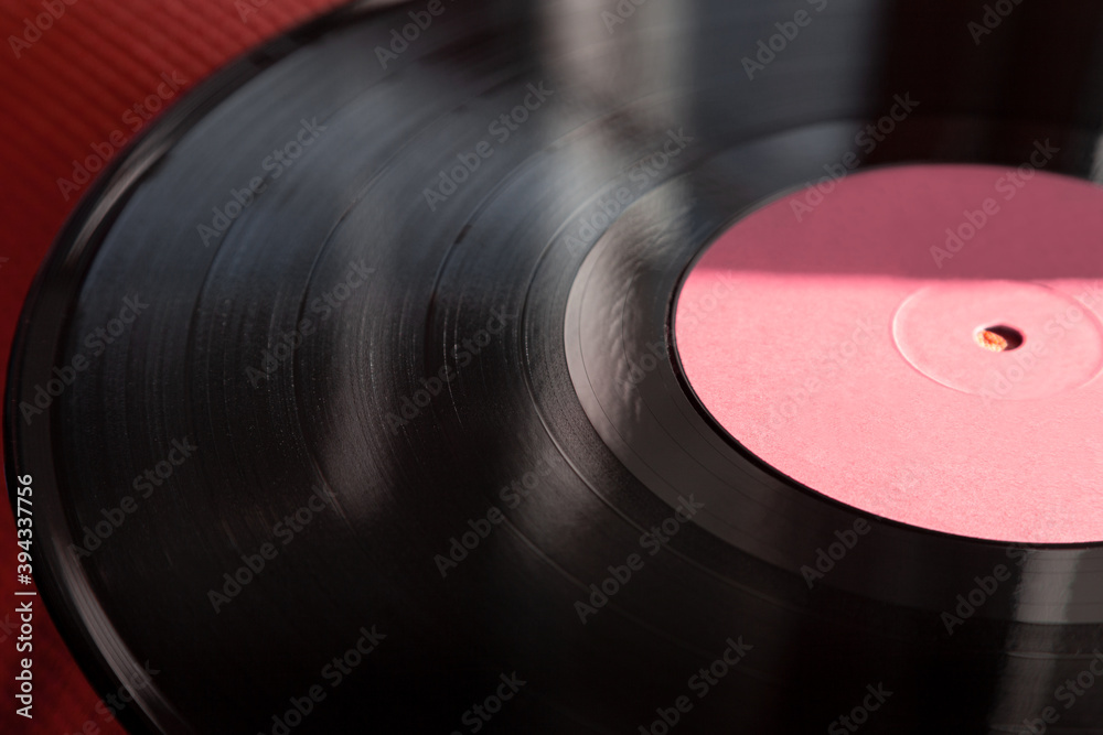 Fragment of vinyl record softly illuminated by the sun, musical background in retro style, selective focus