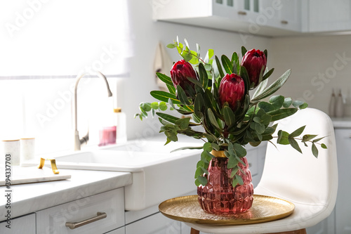 Bouquet with beautiful protea flowers in kitchen, space for text. Interior design