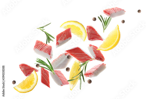 Cut fresh crab sticks, lemon, rosemary and allspice falling on white background