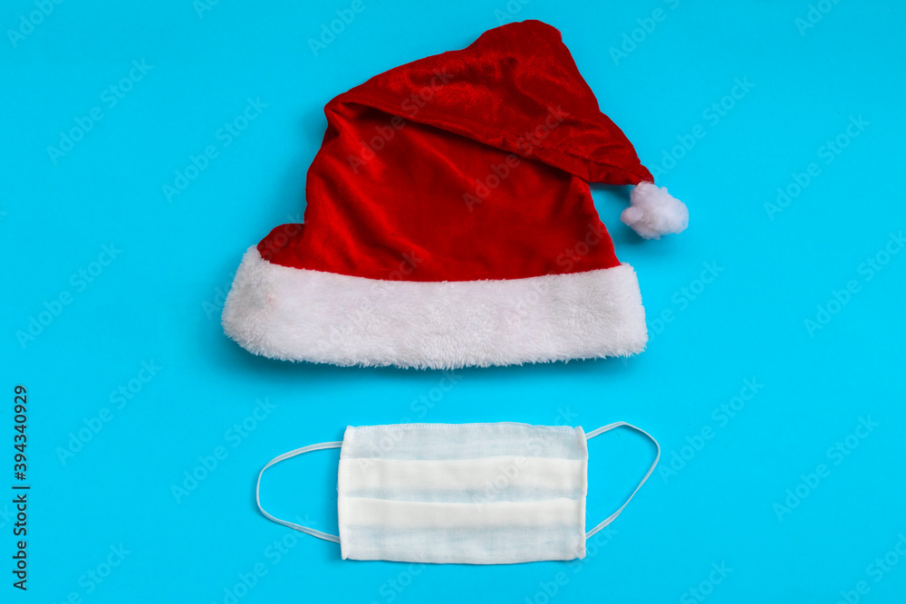 Santa Claus hat and medical mask on light blue background. Christmas and New Year concept. Santa Claus hat and medical mask on light blue background. Christmas and New Year concept.