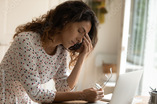 Schilderij op canvas Tired young woman take off glasses suffer from migraine headache overwhelmed with laptop work
