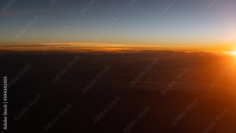Dramatic sunset scenic. View of sunset above clouds from airplane window.