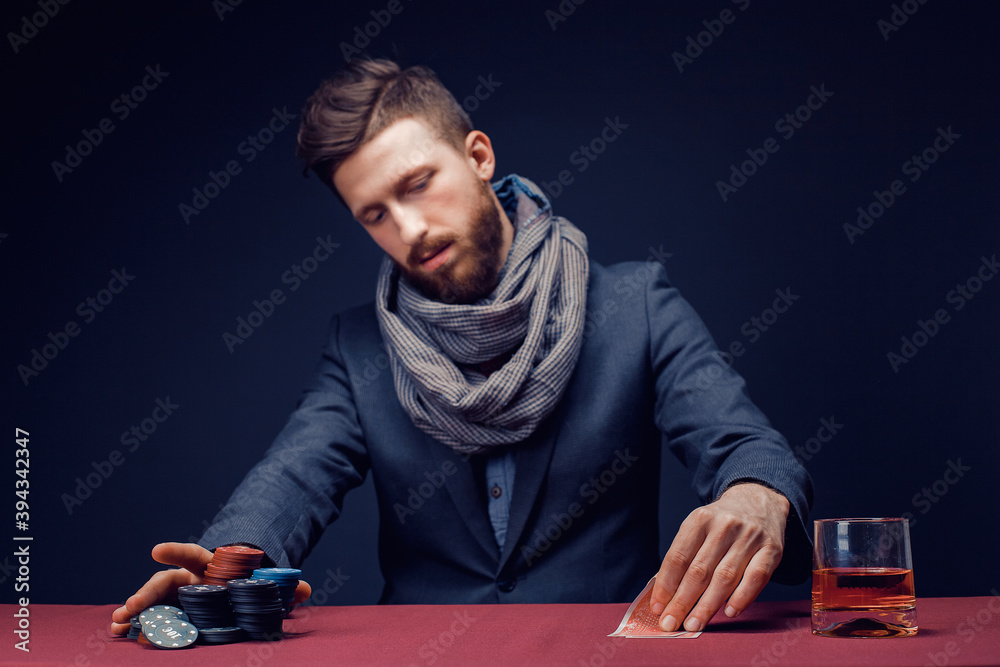 Stylish bearded Man in suit and scarf playing in dark casino, smoking cigar, drink whiskey. Stylish bearded Man in suit and scarf playing in dark casino, smoking cigar, drink whiskey.