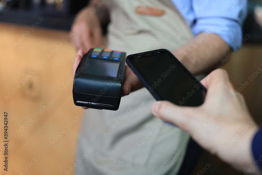 Customer using smartphone for payment to owner at cafe restaurant, cashless technology. Customer using smartphone for payment to owner at cafe restaurant, cashless technology.