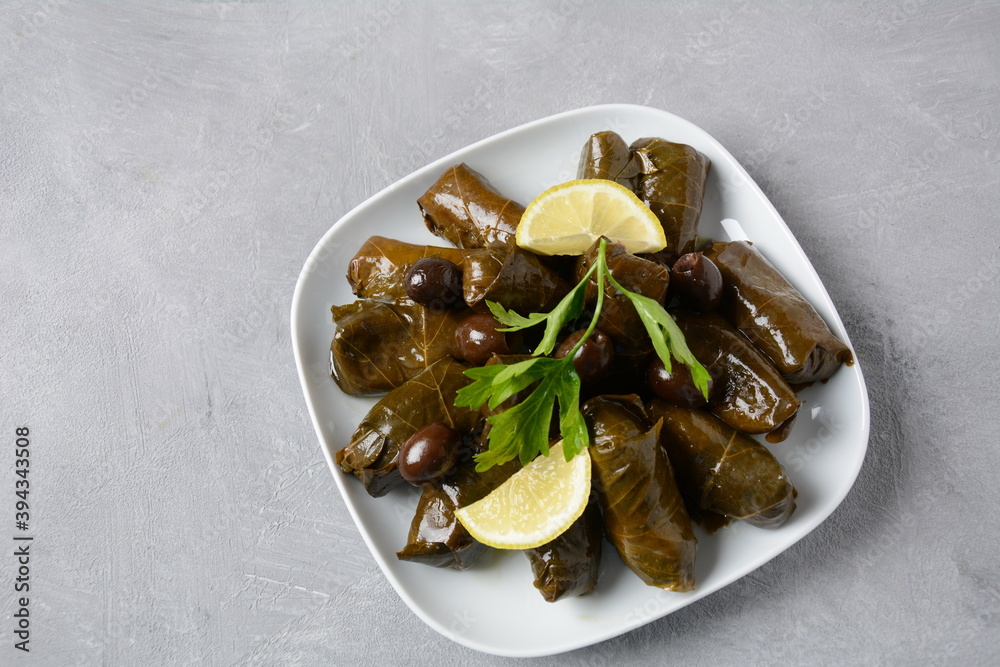 Traditional Greek cuisine. Wrapped rice in grape leaves. Dolma with lemon, spices, various pickled olives and hot peppers. Traditional Greek cuisine. Wrapped rice in grape leaves. Dolma with lemon, spices, various pickled olives and hot peppers.