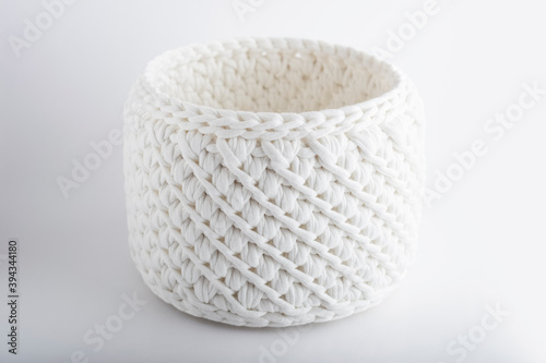 White handmade basket on a white background  with a place for the text. texture of knitted fabric braids. decorative element in the interior. Copy space
