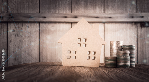 Wood home model on table with finacial coin and business graph in vintage tone