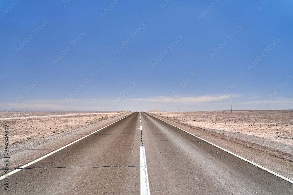 dark, black tarmac road to nowhere leading straight to the horizon in the atacama desert of Chile in South America 