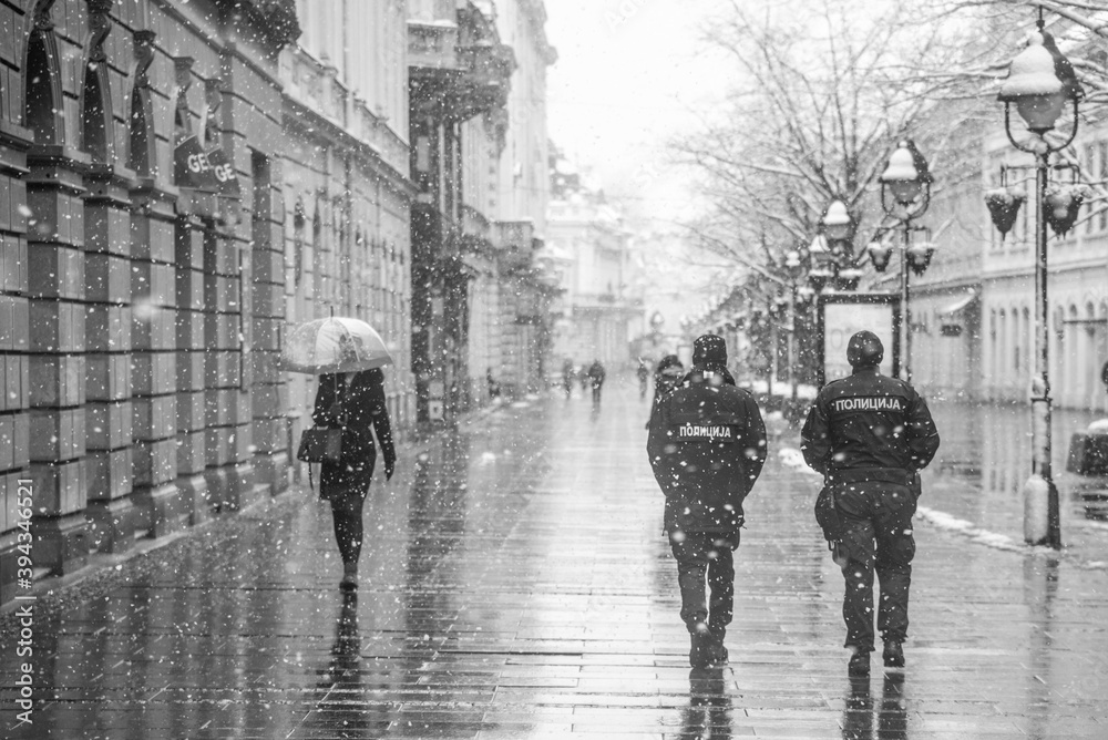 Fototapeta Police patrolling and walking trough empty streets on snowy day in Belgrade,Serbia during police hour due to corona virus covid-19