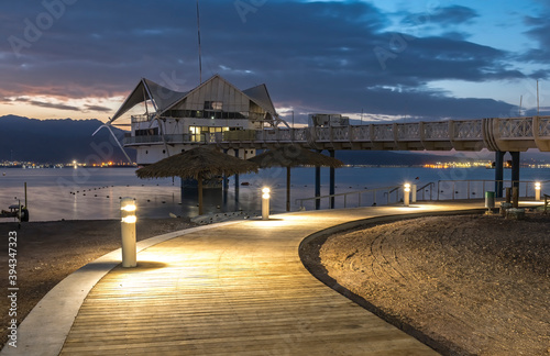 Walking promenade with decorative street lamps and bridge at night